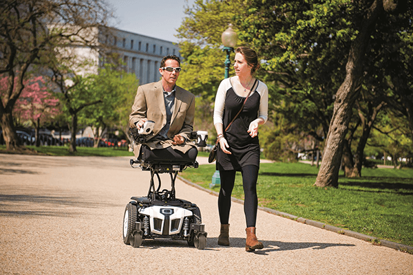Man on powerchair on sidewalk with woman